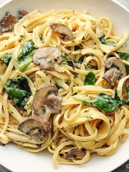 pasta with mushrooms and spinach on white plate