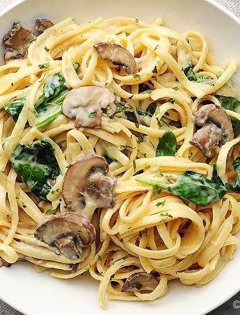 pasta with mushrooms and spinach on white plate