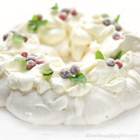 This festive Pavlova Wreath has a crispy crunchy shell and a marshmallowy interior topped with whipped cream, sugared cranberries and fresh mint.