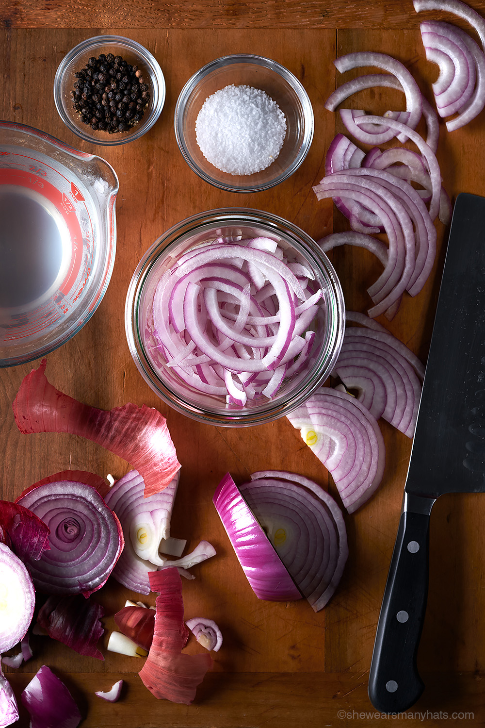 a photo of pickled red onions being prepared with sliced onions, peppercorns, salt and vinegar